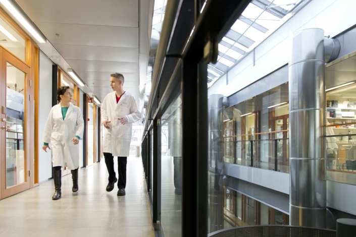 Two researchers walking in Biomedicum