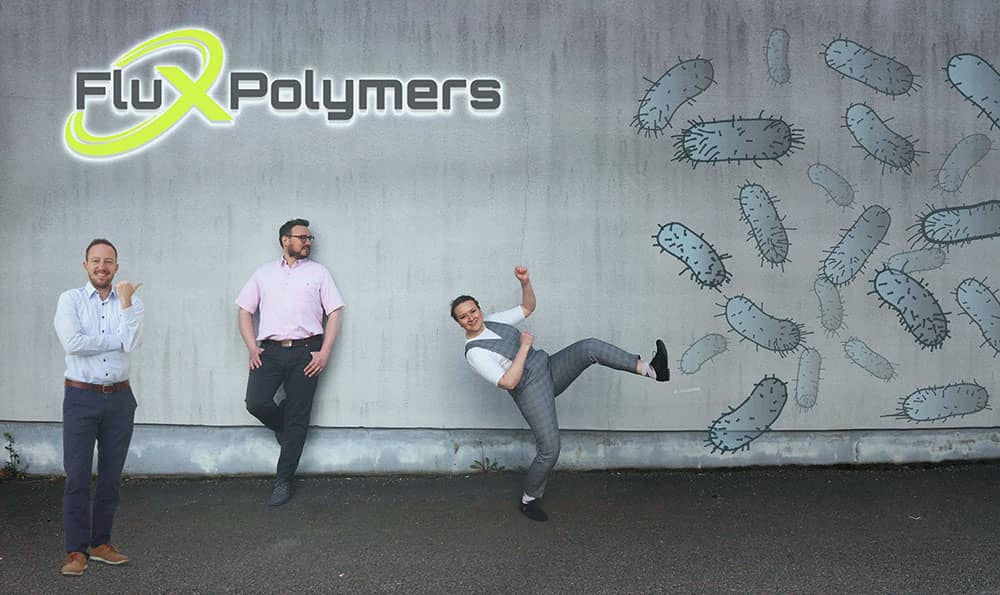 Flux Polymers team members with company logo and bacteria photoshopped