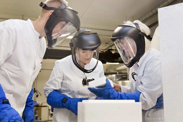 Three researchers with visors and gloves