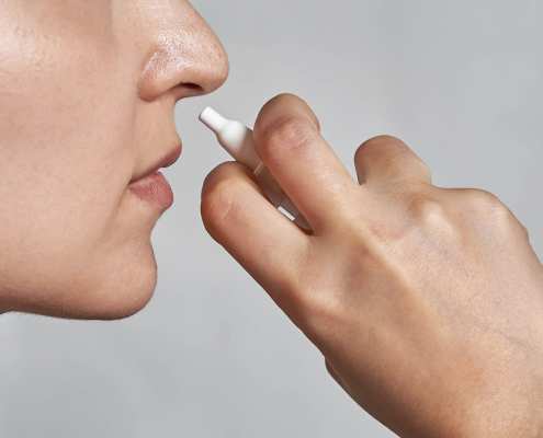 Close-up of unrecognizable woman using nasal spray